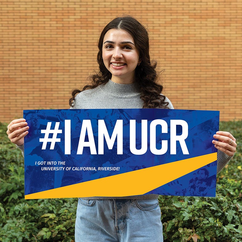 A female student holds a #IAMUCR sign.