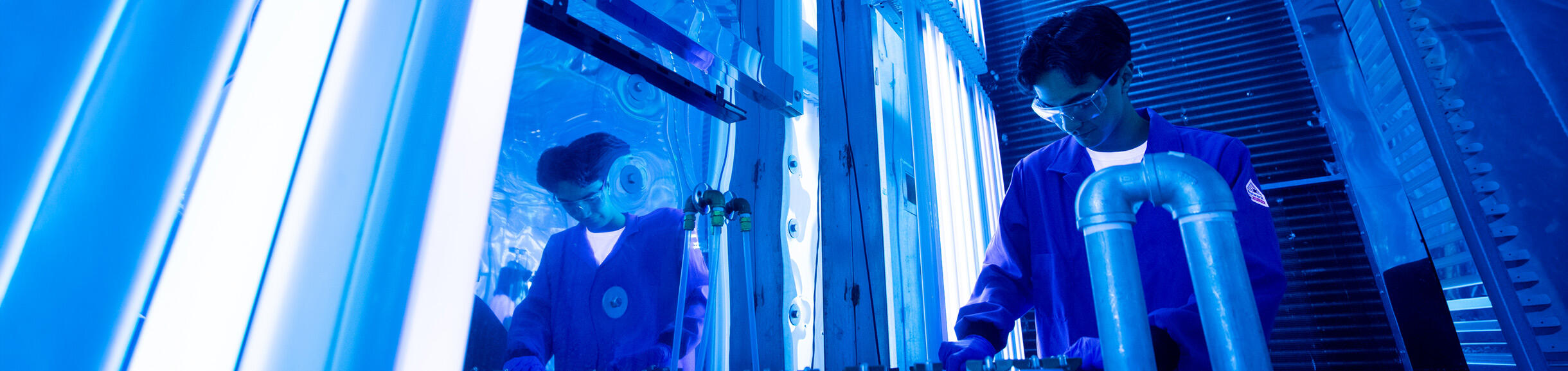 A student wearing a lab coat works inside UCR’s College of Engineering-Center for Environmental Research and Technology.