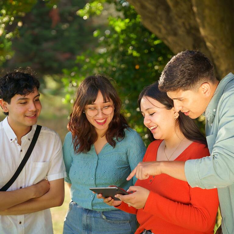 A group of students study information on a tablet during a campus tour.