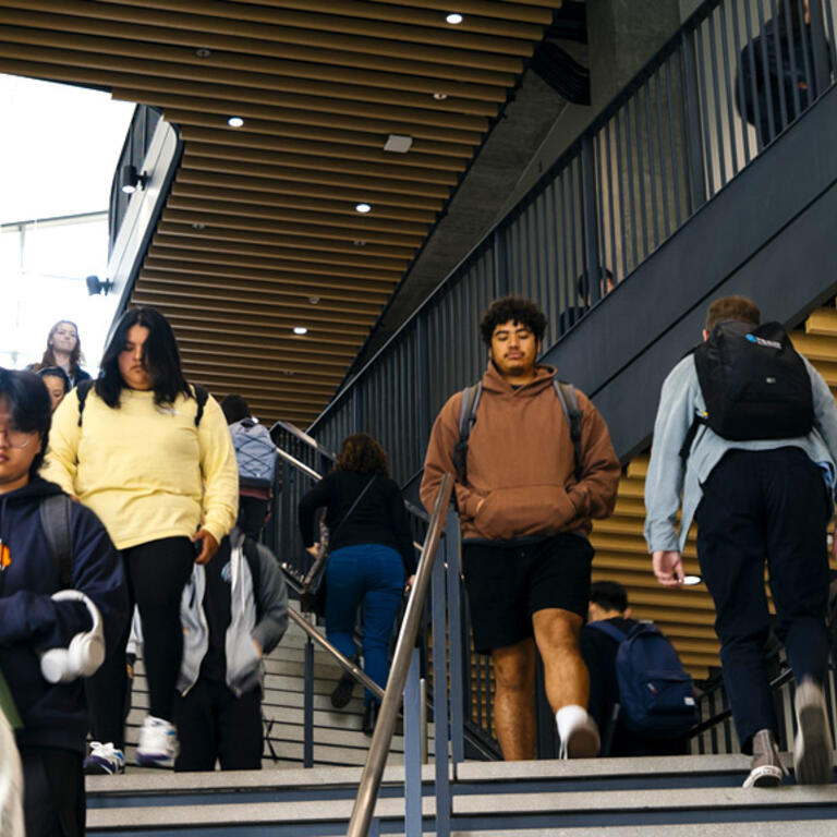 Students on the central staircase inside the modern Student Success Center on the UC Riverside campus.