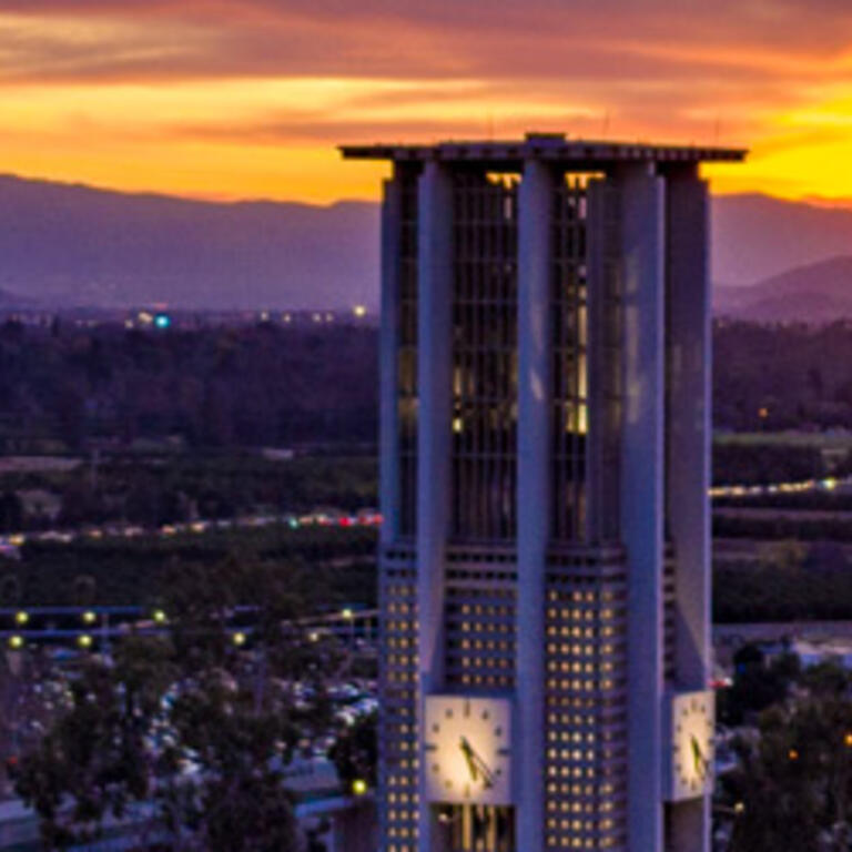 Sunset view of the UC Riverside campus, featuring the illuminated Bell Tower and Box Springs Mountains.