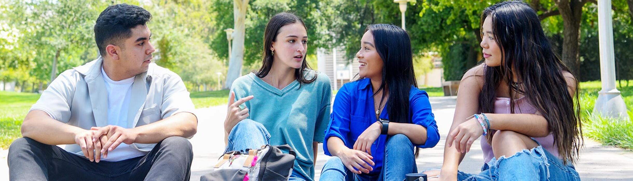 UCR students sit on Hinderaker walkway talking.