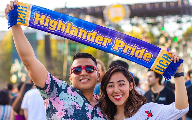 UCR Students holding up a Highlander Pride banner at the Spring Splash concert.